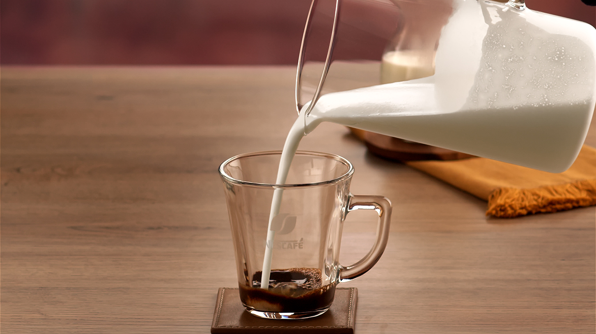 взбитое молоко переливается в бокал с кофе