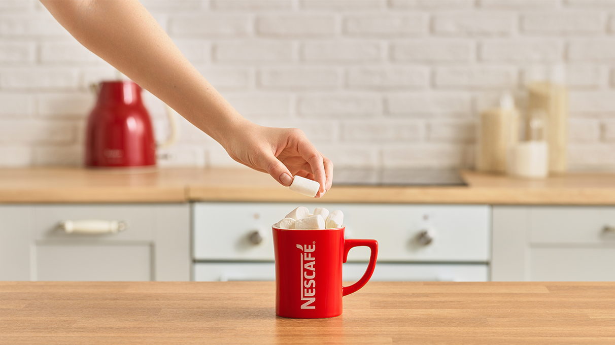 напиток в красной кружке украшается маршмеллоу